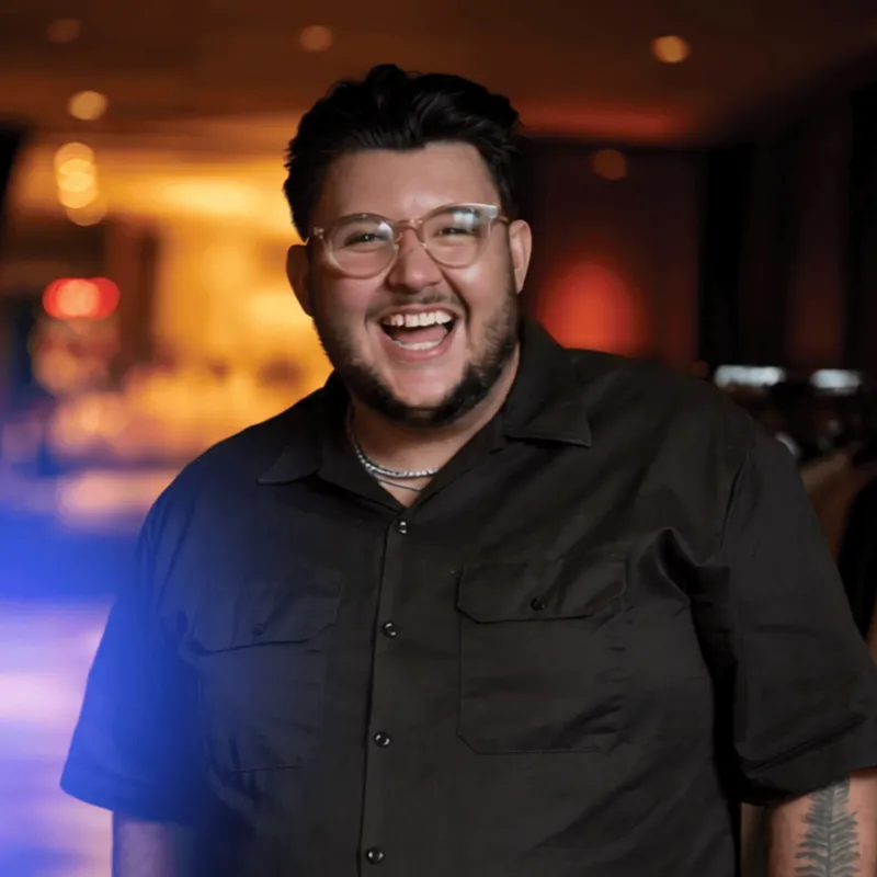 Tom Sharman, laughing, in glasses and a black shirt